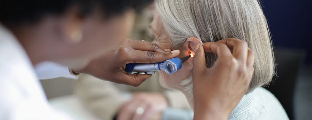 Audiologist examining a patient's ear with an otoscope