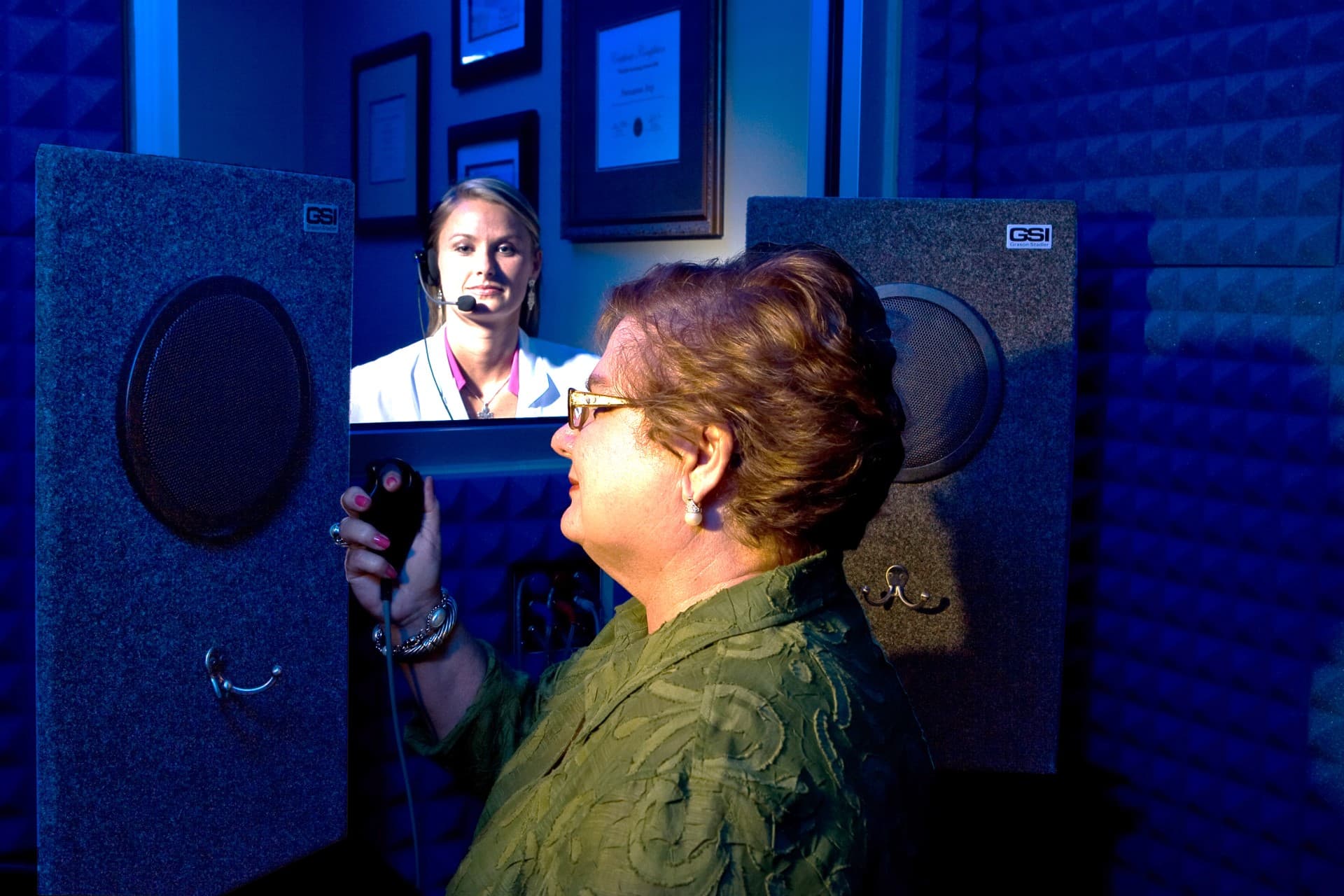 Patient undergoing soundfield hearing evaluation in a testing booth